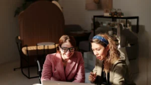 Dos mujeres trabajan frente a una computadora, en una nota sobre inteligencia artificial, selección de talento y reclutamiento libre de sesgos.