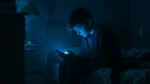 Adolescente sentado en una habitación oscura mira su celular iluminado por una luz azul, en una nota sobre apuestas online, prevención y riesgos para niños, niñas y adolescentes.