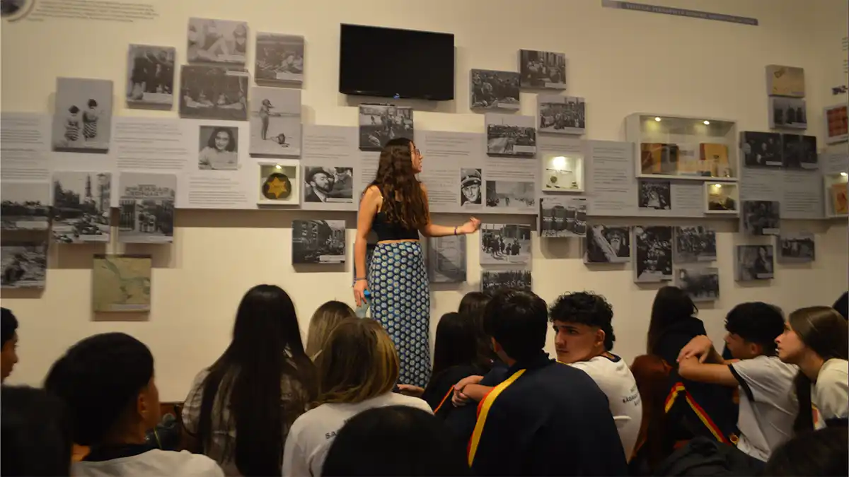 Joven guía explica la historia de Ana Frank ante un grupo de estudiantes en el museo, durante una visita vinculada con memoria, derechos humanos y vacaciones de invierno.