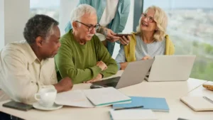 Personas mayores conversan y usan una computadora junto a una persona más joven, en una nota sobre edadismo, cuidado, inclusión intergeneracional y discriminación por edad en Argentina.