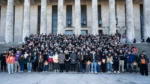 Grupo numeroso de personas posando en las escalinatas frente a un edificio con grandes columnas.