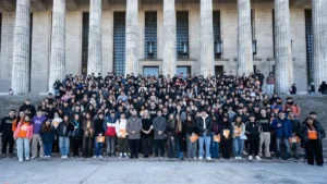 Grupo numeroso de personas posando en las escalinatas frente a un edificio con grandes columnas.