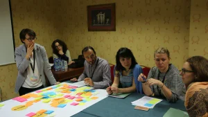 Personas reunidas alrededor de una mesa de trabajo con notas adhesivas de colores distribuidas sobre una lámina.