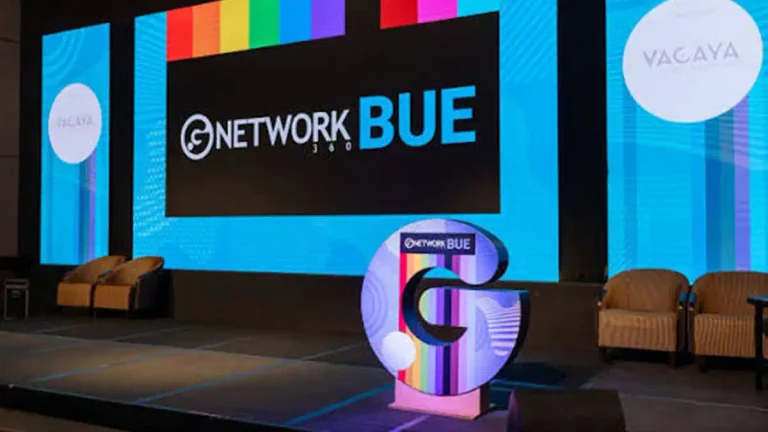 Escenario de GNetwork BUE 360 con pantallas azules y franjas de colores, con sillones a ambos lados.
