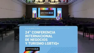 Auditorio vacío frente a un escenario iluminado con pantallas de GNETWORK360 BUE y franjas arcoíris; a la izquierda se ve la bandera del orgullo. En el sector inferior, una gráfica anuncia la 24.ª Conferencia Internacional de Negocios y Turismo LGBTIQ+, el 27 y 28 de agosto de 2026 en Hilton Buenos Aires.