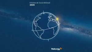 Portada del Informe de Sostenibilidad 2025 de Naturgy sobre un fondo azul estrellado. Un globo terráqueo delineado en blanco ocupa el centro, con líneas orbitales y un punto luminoso amarillo; el logotipo aparece en el sector inferior.