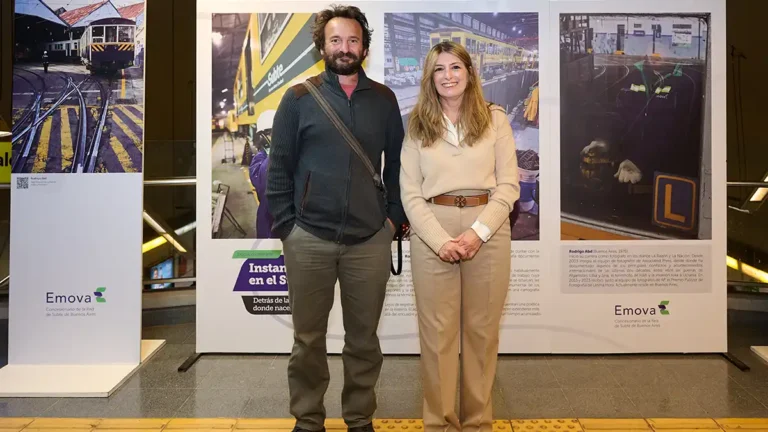 Mariana Giacumbo, directora de Relaciones Institucionales y Medios de Emova, y el fotógrafo Rodrigo Abd posan en la estación Las Heras frente a paneles de la muestra Instantáneas en el Subte 2026, con fotografías de talleres y trabajadores de la red.