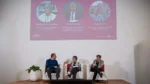 Tres personas participan de un panel frente a una pantalla con la presentación de MIRA sobre mamografía, información, red y acceso.