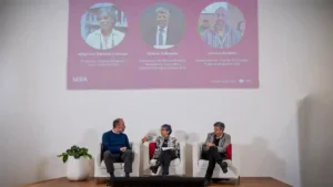 Tres personas participan de un panel frente a una pantalla con la presentación de MIRA sobre mamografía, información, red y acceso.