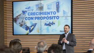 Expositor con micrófono presenta el Reporte de Sustentabilidad 2025 de MetroGAS ante un auditorio, con “Crecimiento con Propósito” en la pantalla.