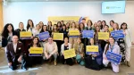 Grupo de participantes de Unstereotype Alliance posando con carteles sobre publicidad sin estereotipos y futuros más inclusivos.