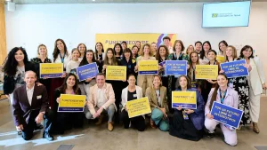 Grupo de participantes de Unstereotype Alliance posando con carteles sobre publicidad sin estereotipos y futuros más inclusivos.