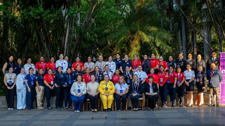 Fotografía grupal de participantes del Programa de Liderazgo OBA para Bomberas 2026, reunidas al aire libre, con uniformes de distintas instituciones de emergencia y credenciales, frente a un entorno arbolado.
