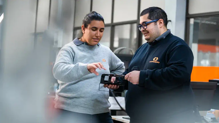 Dos integrantes de CORDERO examinan una pieza industrial durante una actividad de trabajo colaborativo en la empresa metalmecánica.