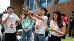 óvenes participan en una actividad grupal de Galicia. Uno de ellos habla con un micrófono mientras otros presentan construcciones realizadas con bloques de colores.